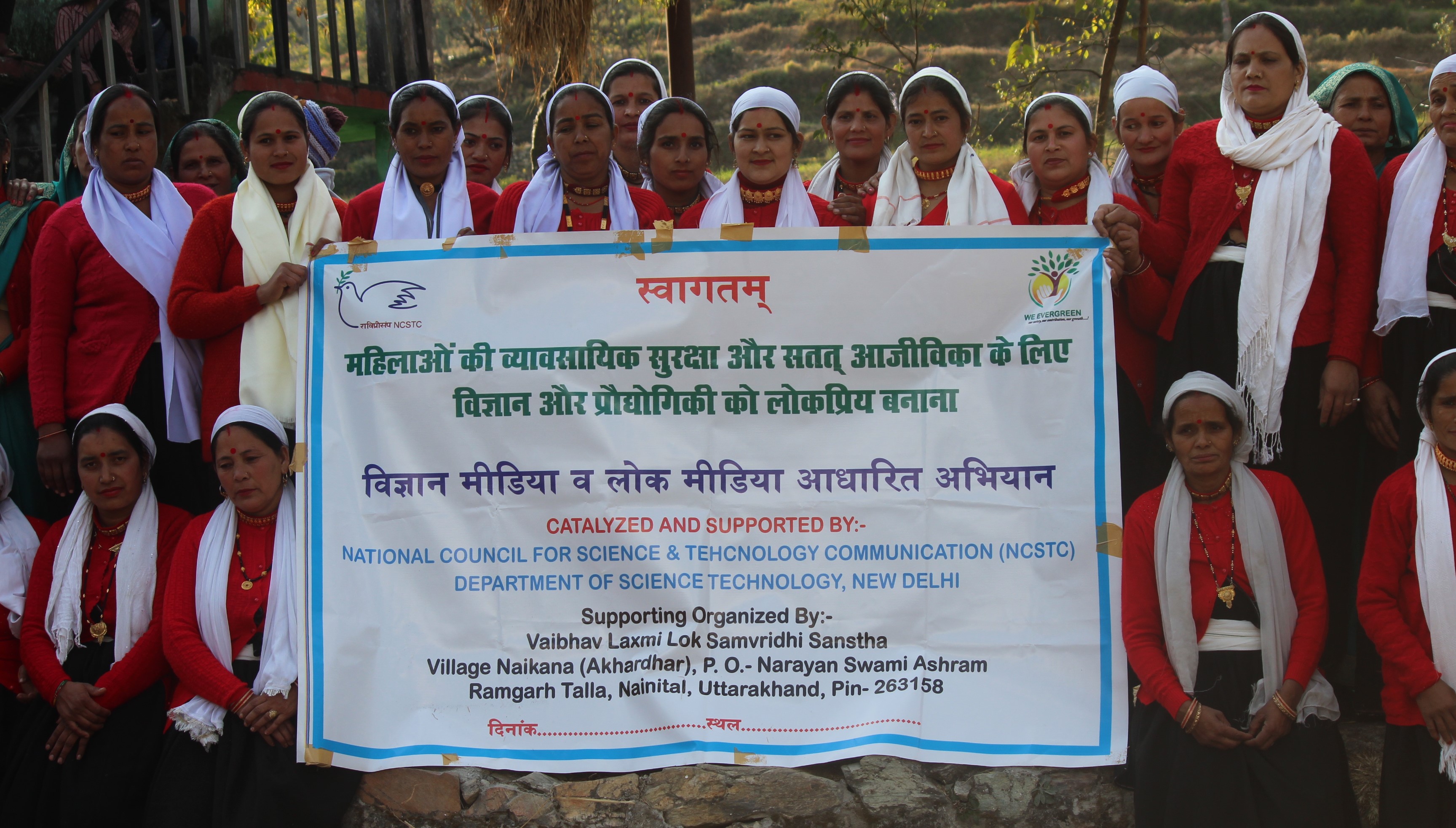 Women gather behind a programme banner about occupational security and sustainable livelihoods.